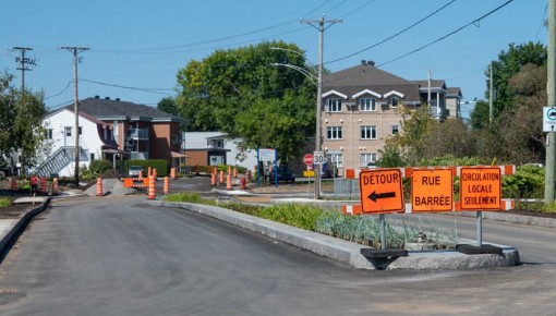 Rue Notre-Dame avec des panneaux oranges de signalisation de détours et plusieurs cônes au loin.