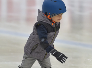 Jeune garçon avec un casque bleu qui patine sur une patinoire.